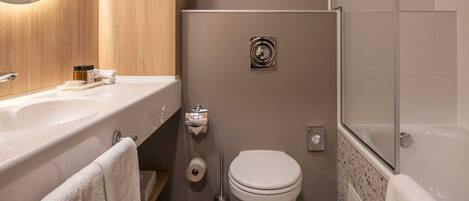 Un baño moderno con tocador de madera, inodoro y zona de ducha.