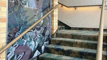Una escalera con alfombra estampada y barandilla, que lleva a una pared con un gran mural.