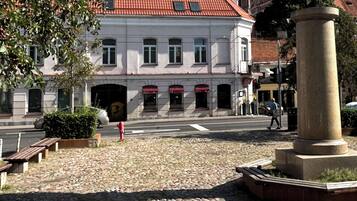 Una plaza adoquinada con un edificio histórico que destaca por su tejado de tejas rojas y una gran esfera decorativa.