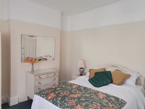 Une chambre à coucher avec un lit, une commode, un miroir et une lampe.