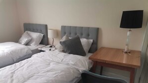 A hotel room with two single beds, a bedside table with a lamp, a chair, and a small desk. - 3 Minutes to Train station large town house with 5 bedroom, 6 bed, sleep 8 guest (Ilford)