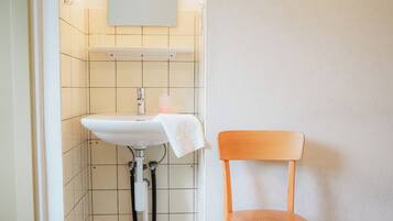 A bathroom with a sink, a mirror, and a wooden chair.