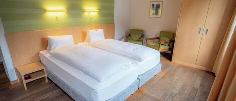 A double bed with a wooden headboard, a small bedside table, and two wall-mounted lights.