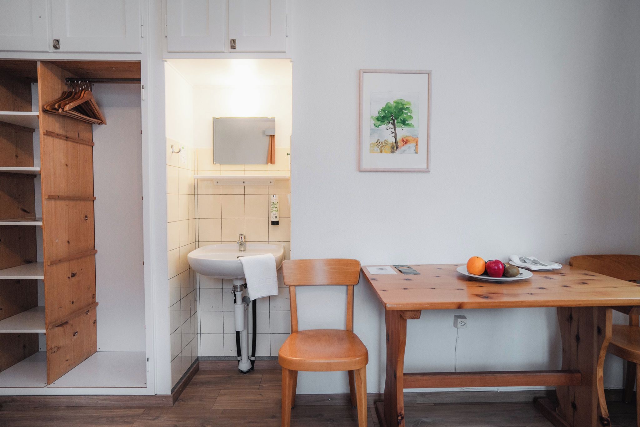 Une cuisine de taille réduite, avec un meuble en bois, un évier et une table à manger avec des chaises.