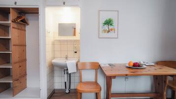 Una cocina compacta con un armario de madera, un lavamanos y una mesa de comedor con sillas.