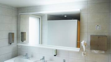 A modern bathroom with two sinks, a large mirror, and a step for accessibility.