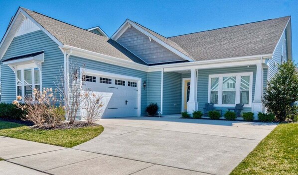 Ein zweistöckiges Haus mit Garage, überdachter Veranda und gepflegtem Rasen.