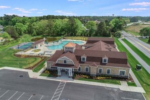 A large building with a swimming pool, tennis court, and landscaped garden. - Ocean View * 5BR Luxury Beach Resort Home (Ocean View)