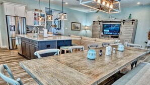 A modern kitchen with a central island, built-in appliances, and a dining area with a long wooden table.