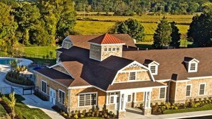 A large house with a stone exterior, multiple chimneys, and a large driveway.