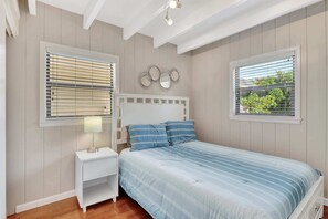A bedroom with a bed, nightstands, a lamp, and a wall-mounted mirror.