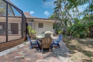 A patio with a table and chairs, a covered seating area, and a view of a house with a screened porch.