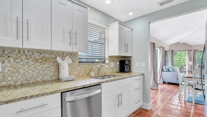 A modern kitchen with white cabinets, a tiled backsplash, and a stainless steel dishwasher. - A Private Oasis Complex in Naples (Naples)