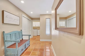A hallway with a bench, a framed sign, a mirror, and a kitchen area. - A Private Oasis Complex in Naples (Naples)