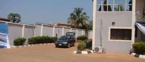 A building with a car parked in front, a clear sky, and a palm tree in the background.