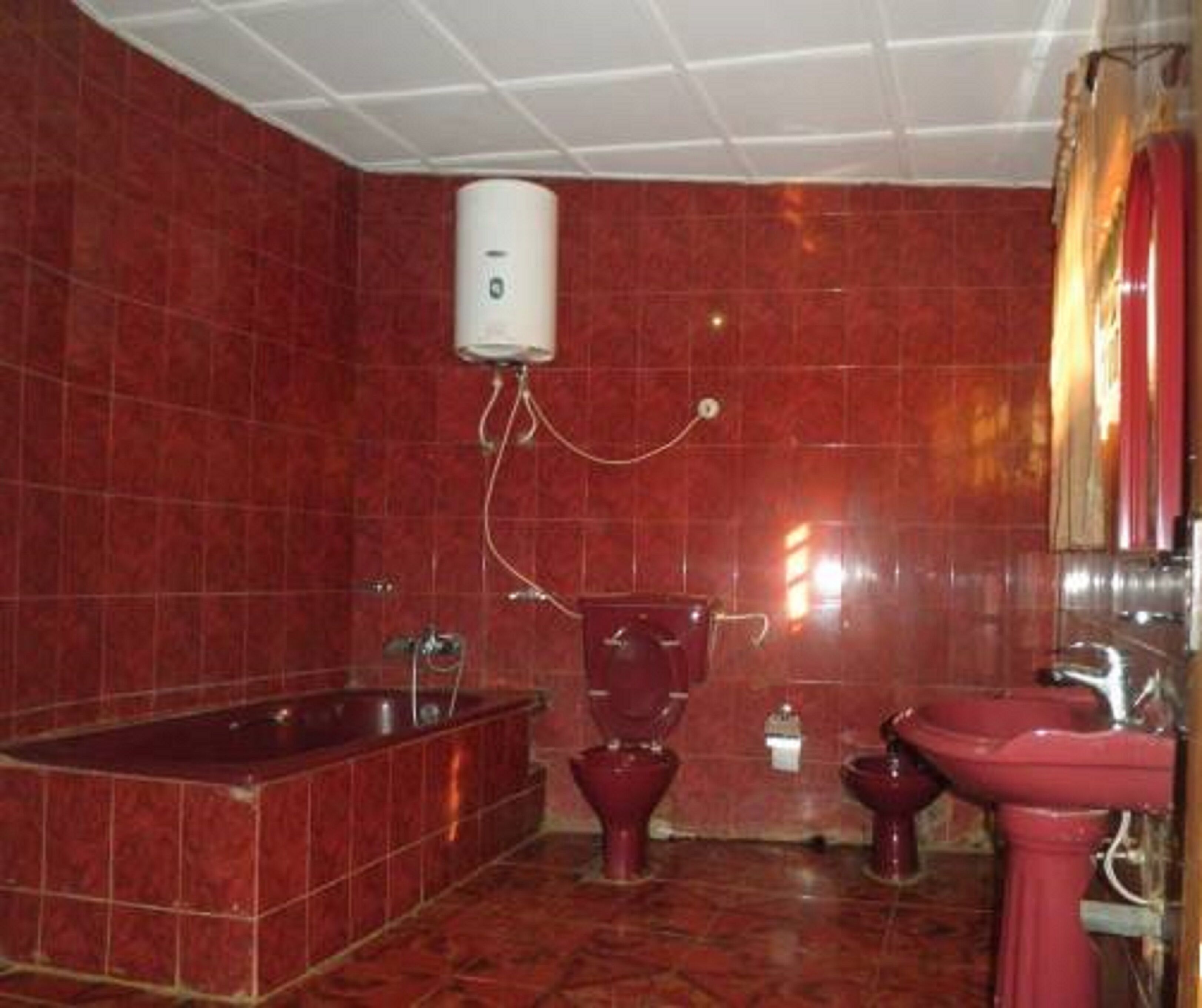 Un baño con azulejos rojos, una bañera, un inodoro y un lavabo.