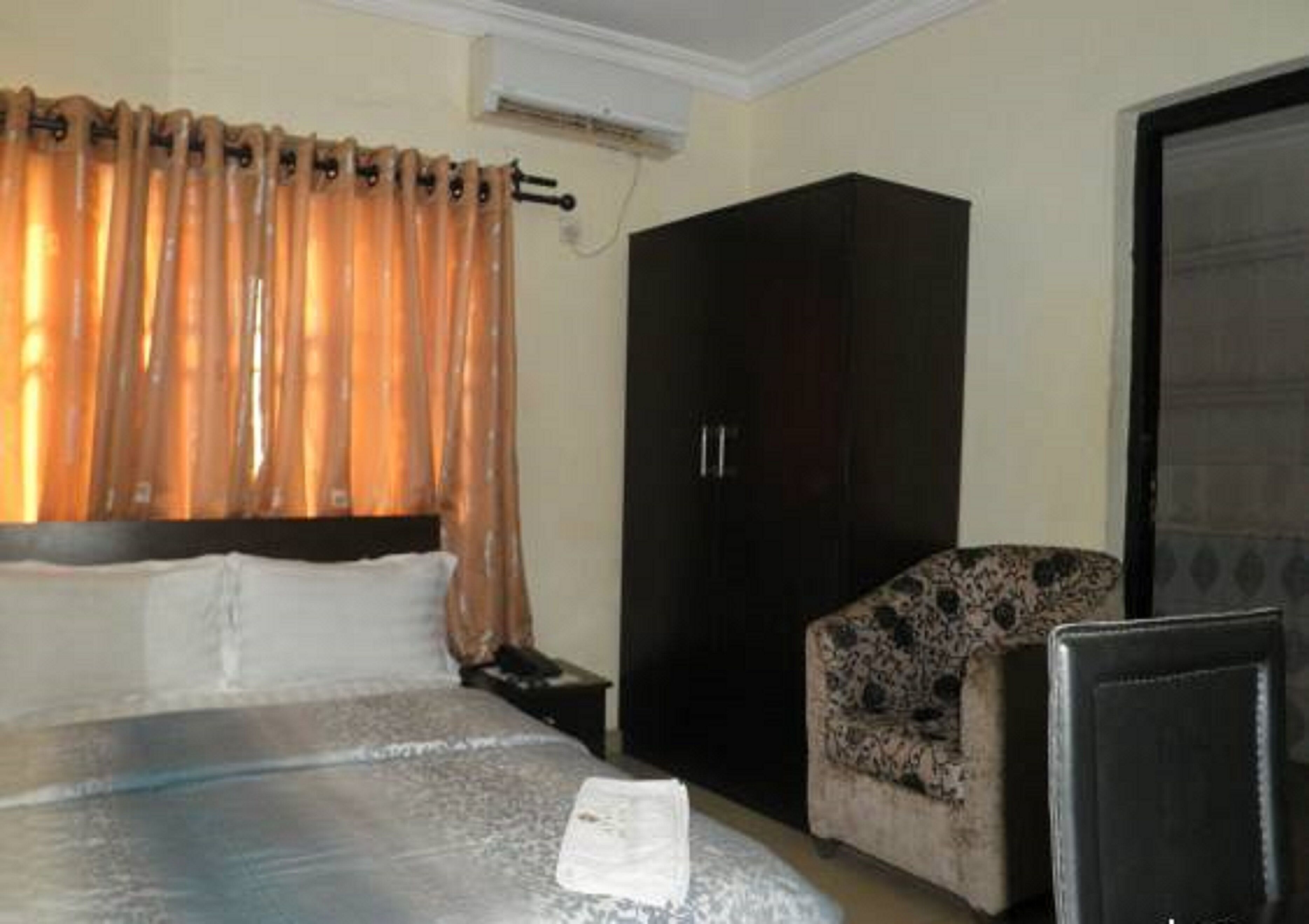 Una habitación de hotel con cama, armario, silla y escritorio.
