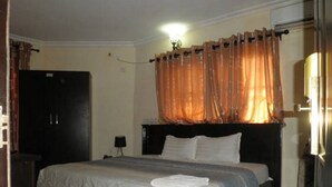 Habitació d'hotel amb un llit, un armari, una tauleta de nit i una làmpada.
