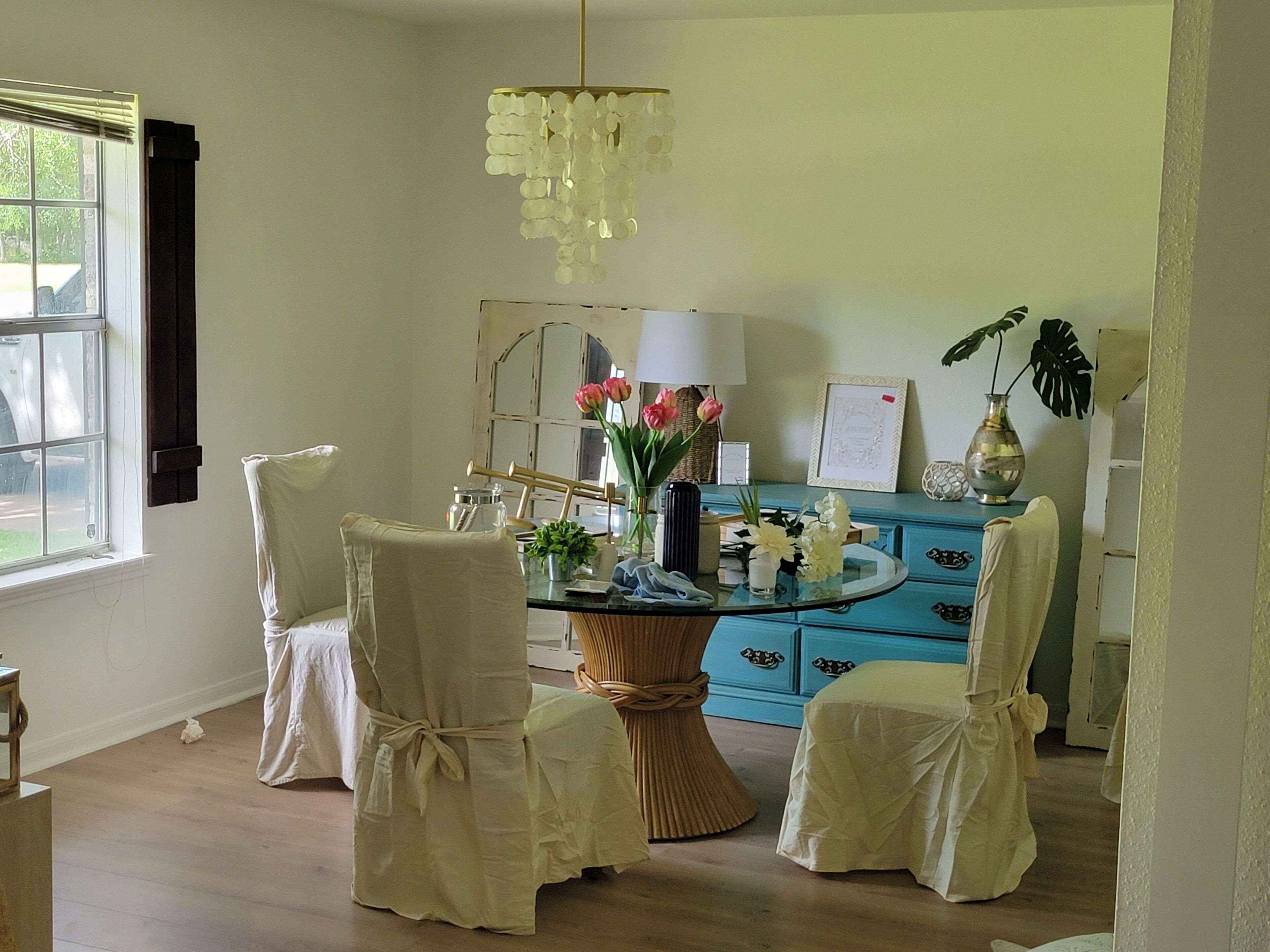 Um quarto com uma mesa de jantar rodeada por cadeiras, um aparador azul e um candelabro.