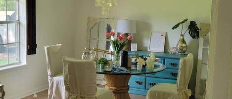 Um quarto com uma mesa de jantar rodeada por cadeiras, um aparador azul e um candelabro.