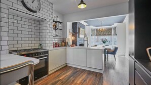 Une cuisine moderne avec des meubles blancs, une cuisinière encastrée et un plancher en bois.