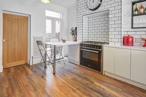 A kitchen with a white tiled backsplash, a stove, and a dining area with a table and chairs.