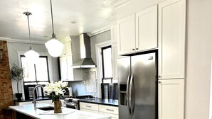 A modern kitchen with a central island, stainless steel appliances, and wooden flooring. - Brewery District Homestead  (Columbus)