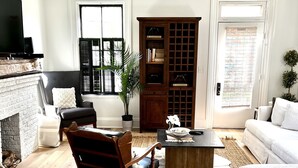 A living room with a fireplace, a wooden cabinet, a sofa, a coffee table, and a rug. - Brewery District Homestead  (Columbus)