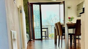 A hallway with a tiled floor leading to a dining area with chairs and a table. - Sonhozinho House Colico, Beautiful Villa with Lake and Mountain View (Lombardia)
