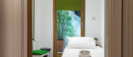 Un dormitorio con una cama, una silla verde y una pequeña mesa.