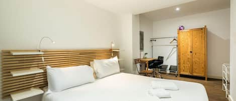 Habitació d'hotel moderna amb un llit gran, taules de nit, escriptori i armari.