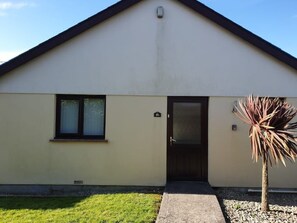 A single-story building with a dark roof, a front door, and a small window. - Large 3 bed bungalow set in Woodland grounds near Tamar lakes and local beaches (Kilkhampton)