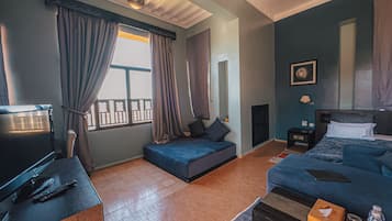 A modern bedroom with a bed, a sofa, a TV, and a desk.