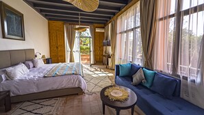 A bedroom with a bed, a sofa, a small table, and a ceiling fan. - Kasbah Agounsane (Ourika)