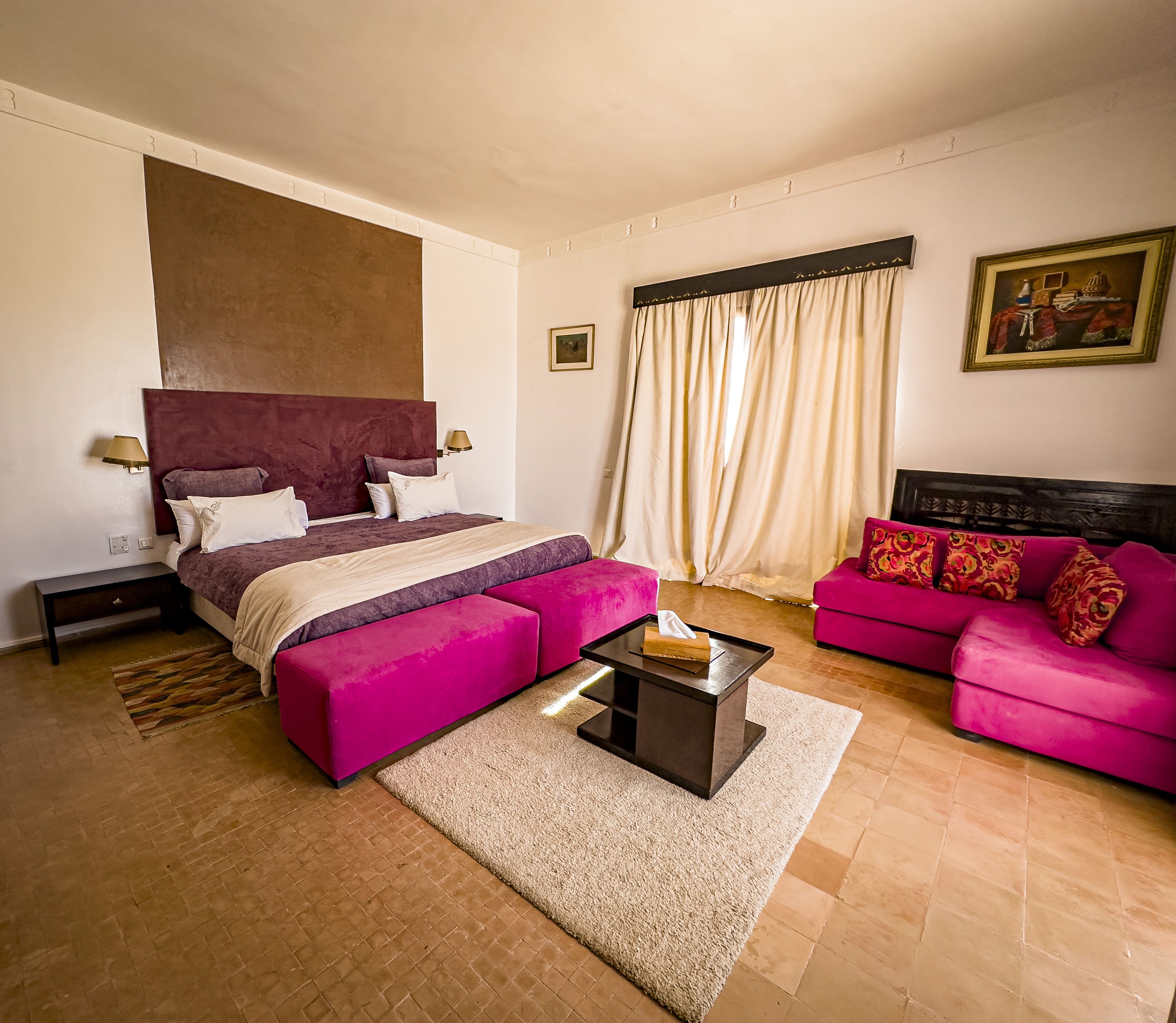 A bedroom with a large bed, a sofa, a nightstand, and a bedside table.