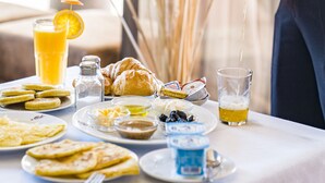 A breakfast table with plates of food, a glass of orange juice, and a teapot. - Kasbah Agounsane (Ourika)