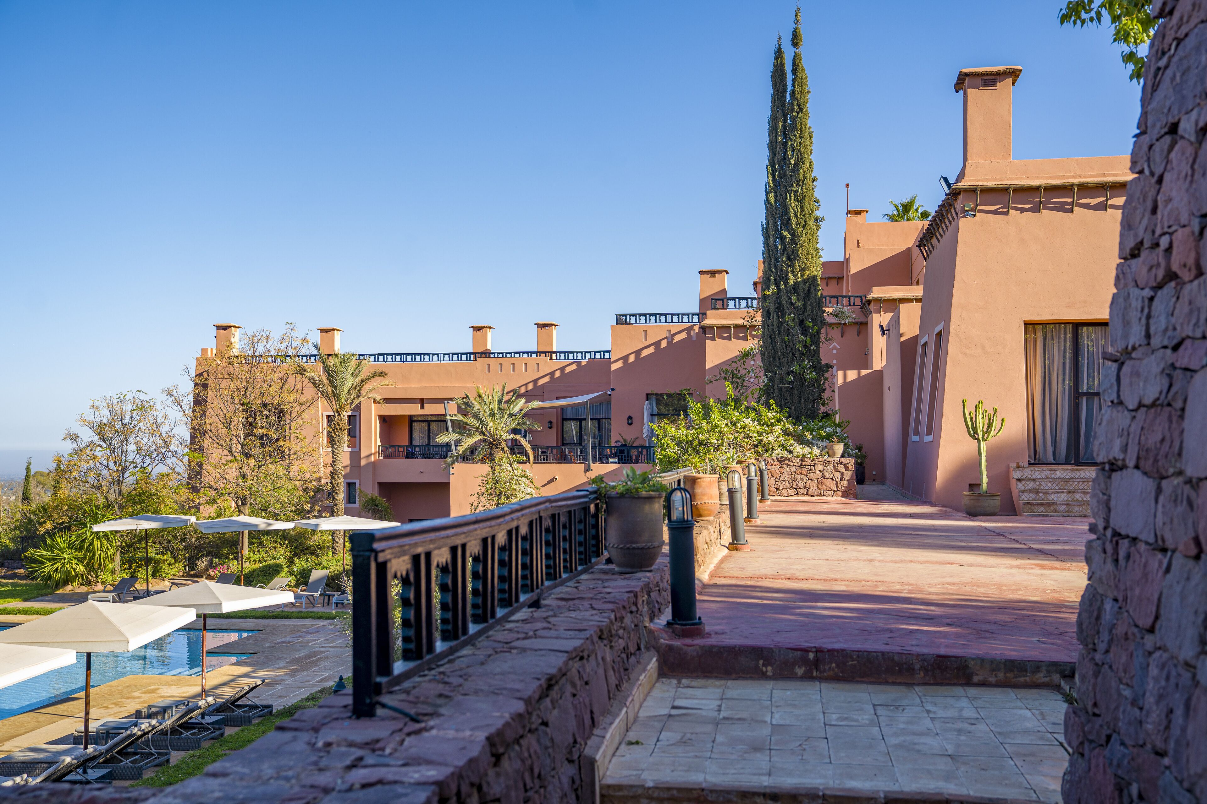 A resort with a pool, lounge chairs, and a stone pathway leading to the building.