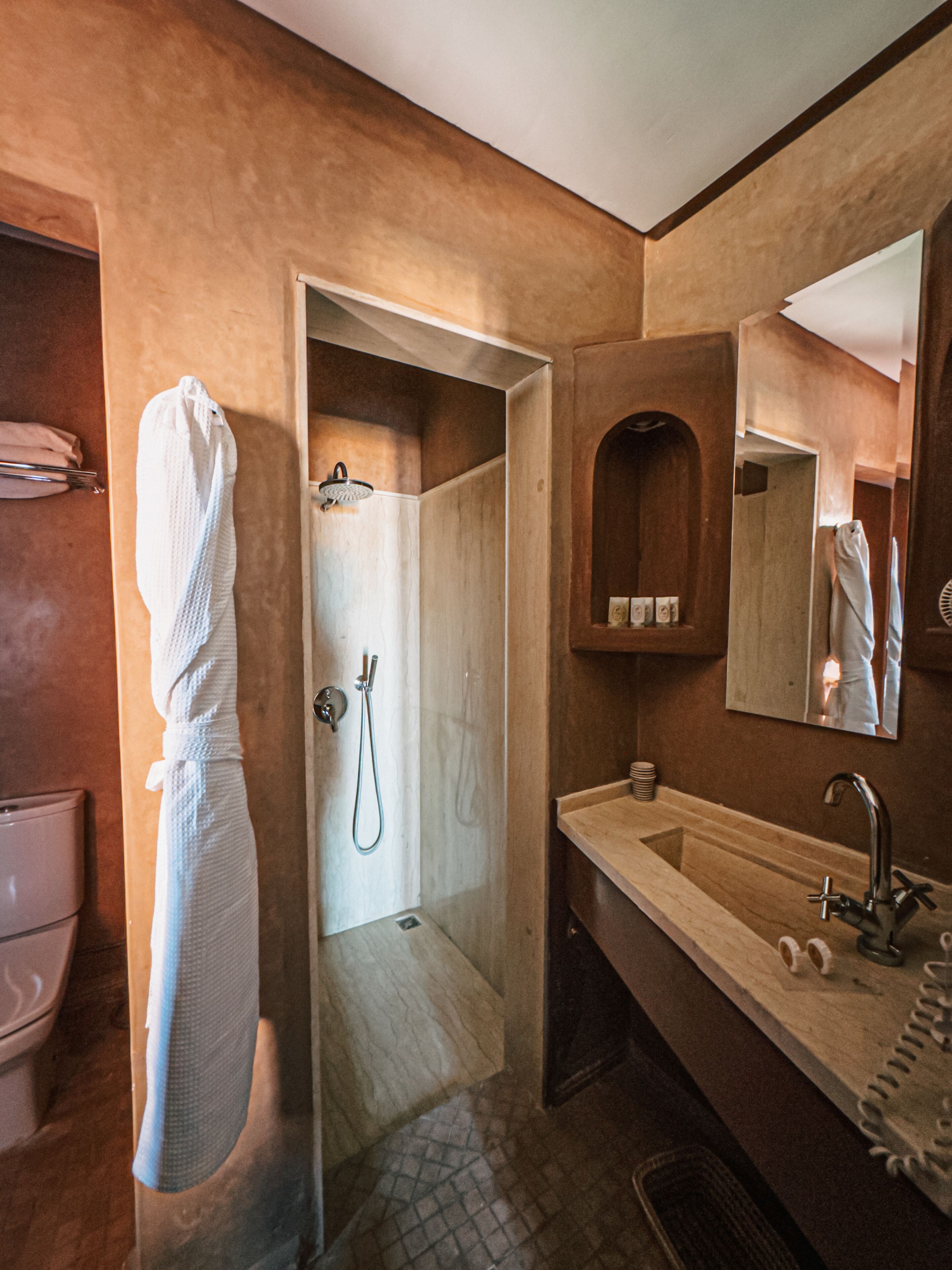 A bathroom with a wooden vanity, a mirror, a shower, and a towel rack.