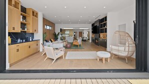 Ein modernes Interieur mit Holzausstattung, einer Couch, einer Essecke und einem Korbstuhl.