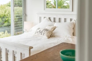 A bed with white bedding, a window with blinds, and a framed picture above the bed. - Encounter Bay Family Escape – Sea Views, Games Room & Walk to The Bluff (Encounter Bay)