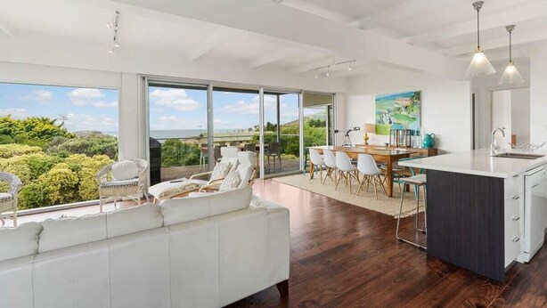 Una cocina moderna con una isla grande, comedor con sillas y vistas al exterior.
