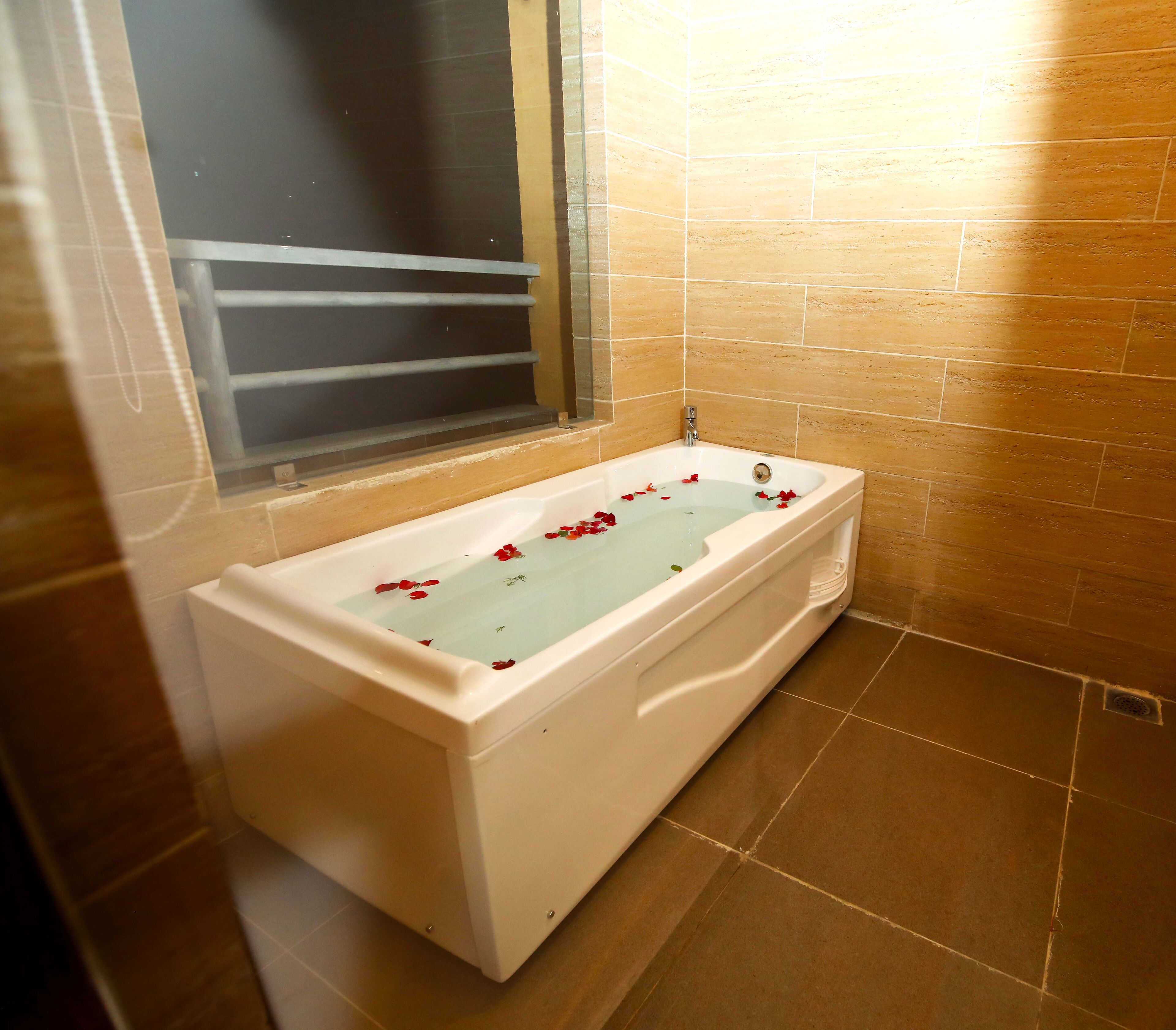 Une salle de bain avec une baignoire, des murs carrelés et une fenêtre.