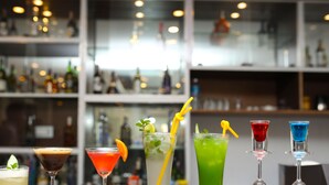 A bar with various cocktails, including a martini, a red drink, a green drink, a red drink in a martini glass, and a blue drink in a martini glass. - Ashoka Resort Pvt. Ltd (Kabilas)