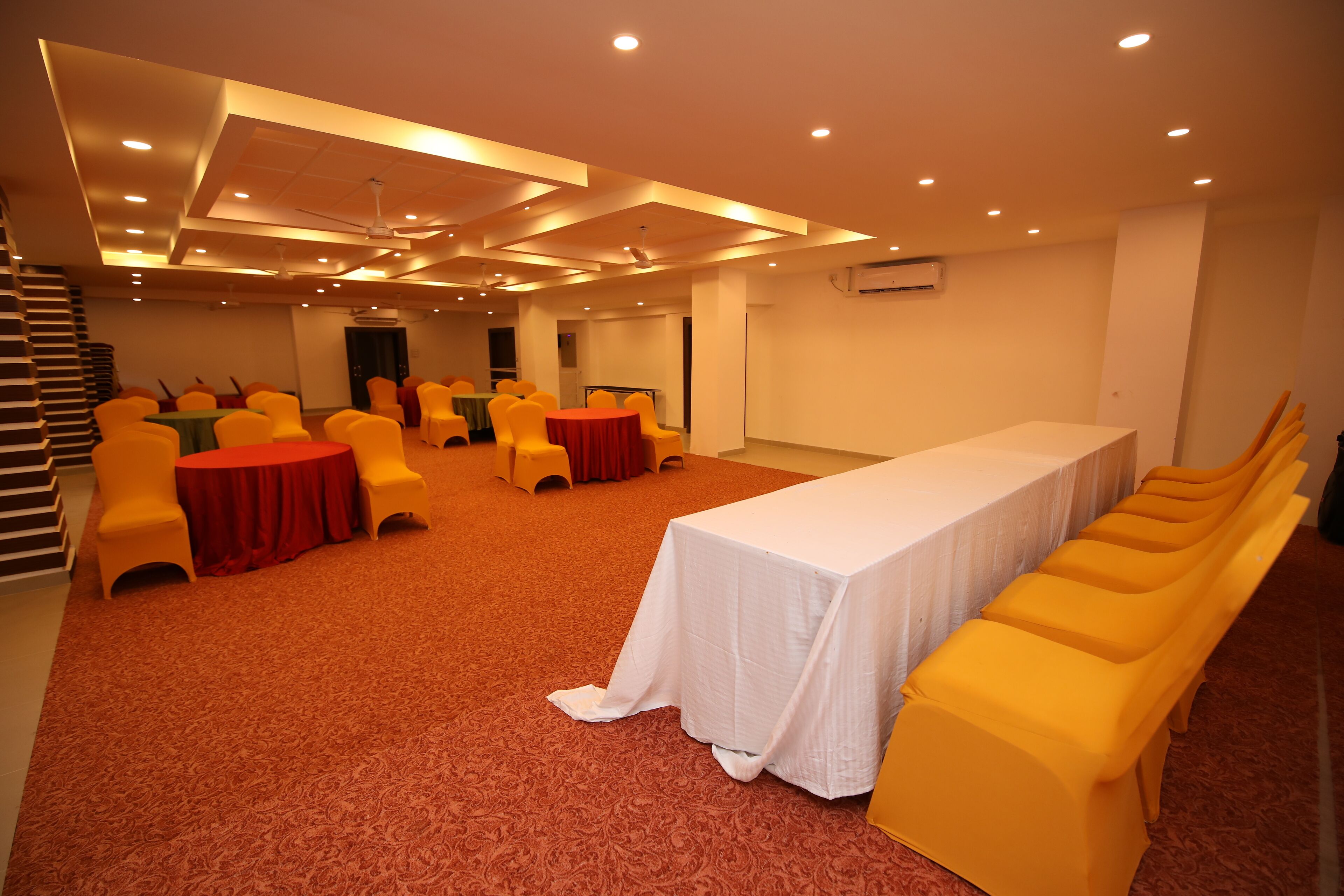 Un salón de conferencias con sillas amarillas, una mesa larga y suelo cubierto de alfombra.