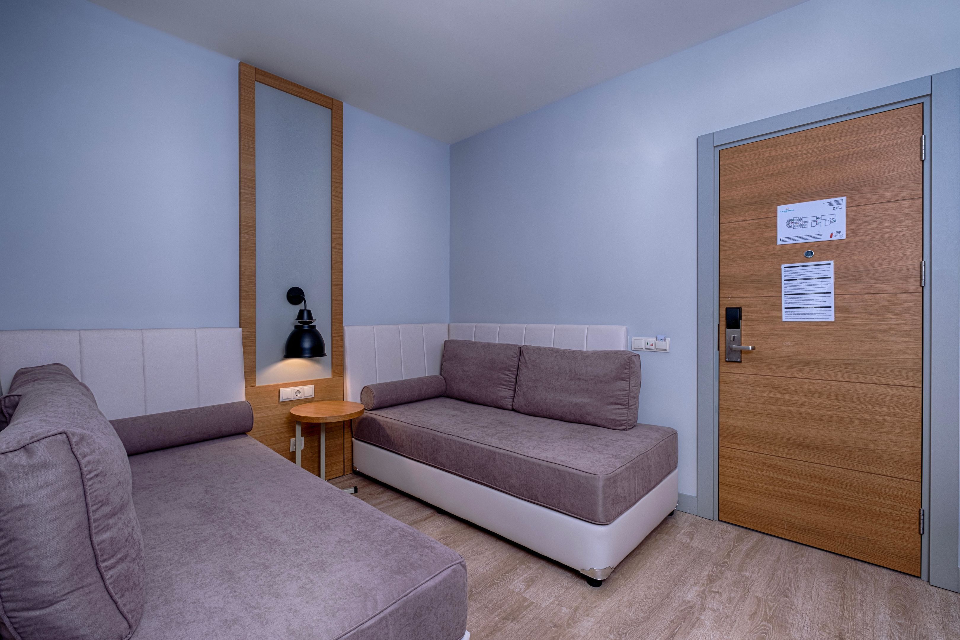 A modern room with a sofa, a small table with a lamp, and a door with a sign.