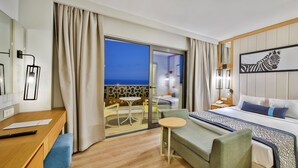 A hotel room with a bed, a desk, a chair, a small table, and a view of the sea. - Calido Maris Hotel (Manavgat)