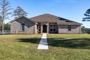 Stroll up to the charming single-story home with a gabled roof, flanked by windows and a garage door.