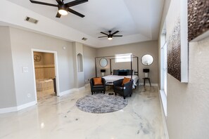 Relax in a spacious bedroom with a large bed, armchairs, and a round rug.