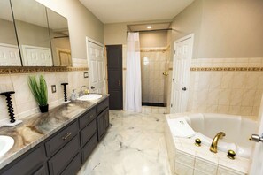Une salle de bain avec un meuble-lavabo à deux vasques, une baignoire, une douche et un grand miroir.