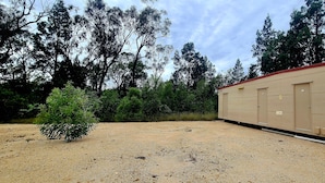 A single-story building with a beige exterior, a red roof, and a gravel driveway. - Bush getaway -technology free, soaking up the Aussie Bush (Crossroads)